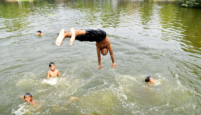 Young take relaxing bath in the pond water for relief from intense heat.